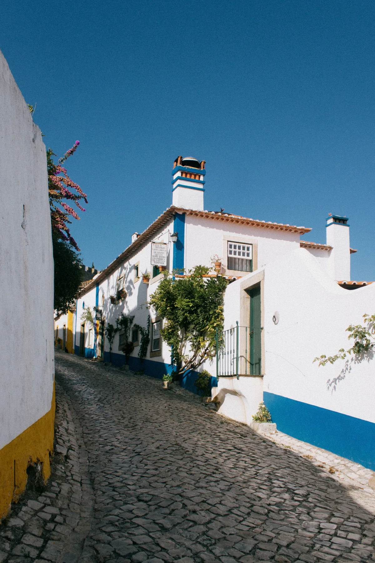 A whitewashed cobblestone lane with blue trim inside Óbidos