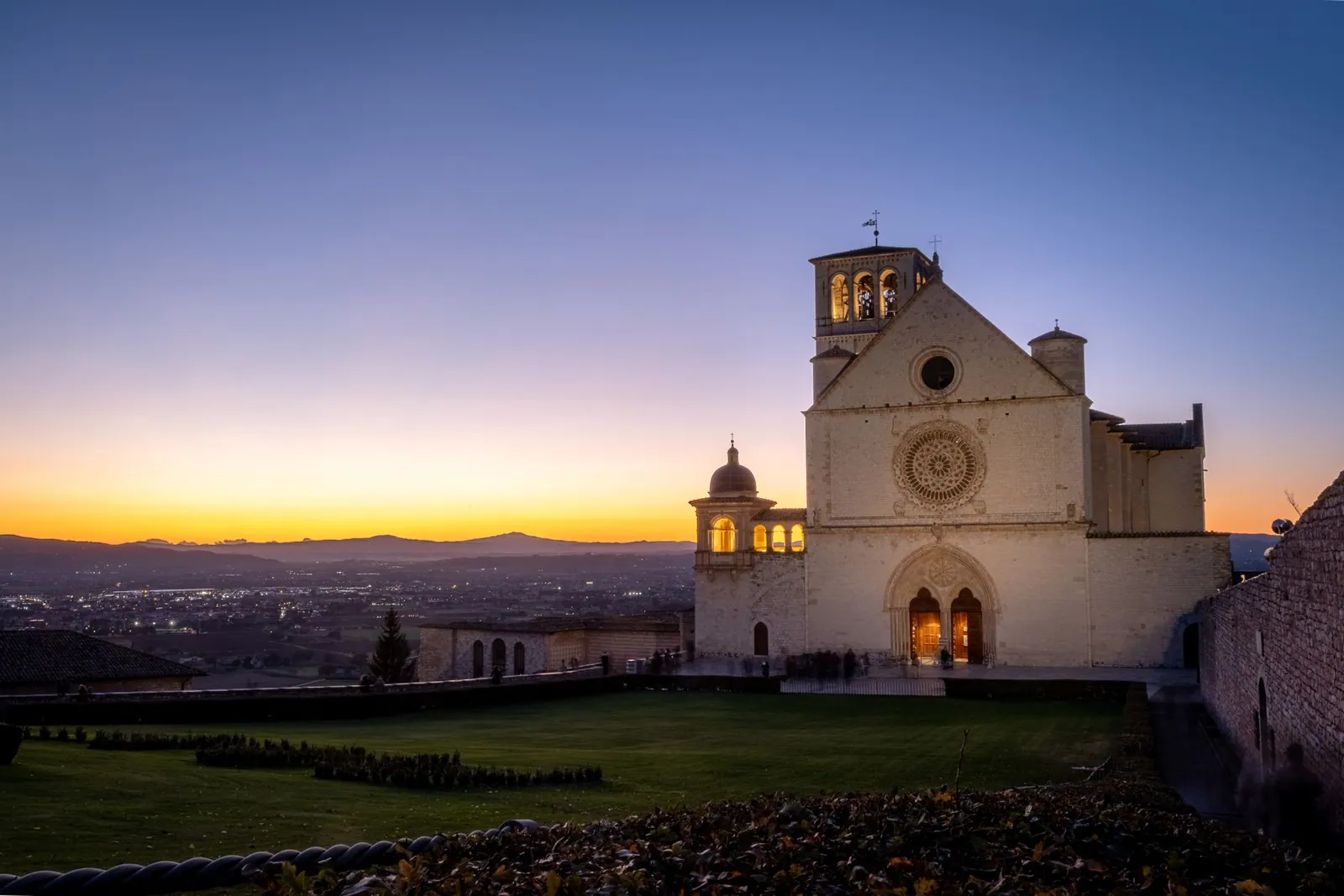 The Basilica of Saint Francis in Assisi illuminated at dusk above the Umbrian valley