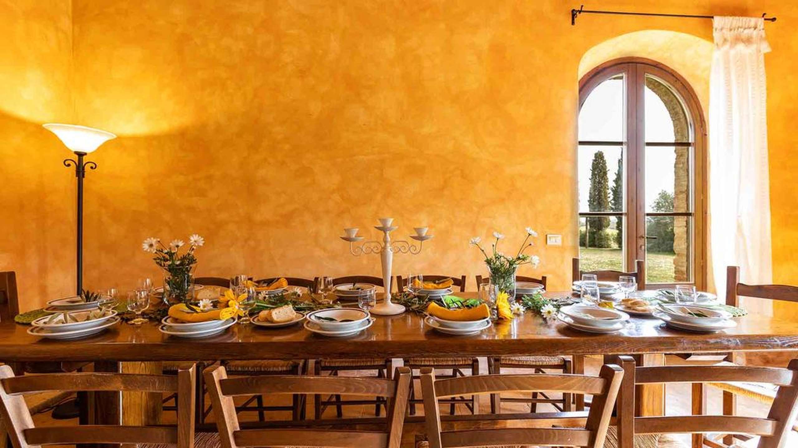 A long dining table inside a sunlit Tuscan villa