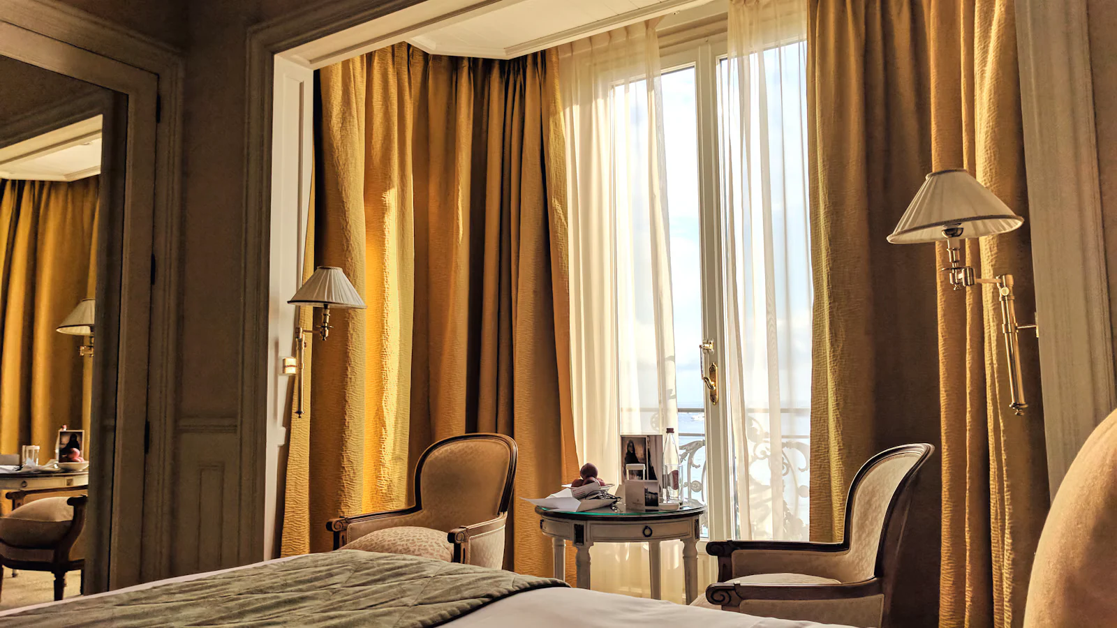 Refined European hotel room with warm drapery, a neatly dressed bed and classic seating