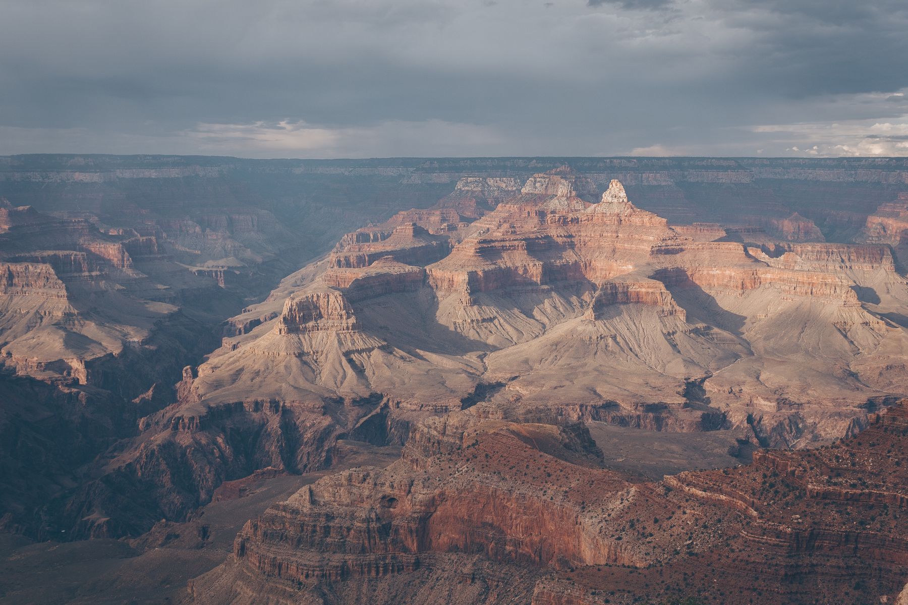 Layered cliffs and mesas beneath storm light at the Grand Canyon